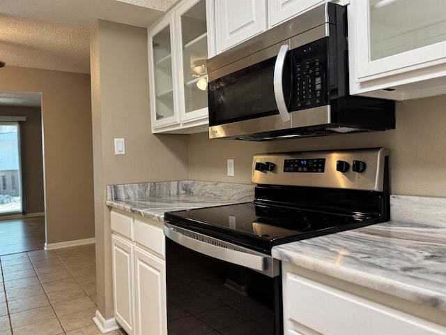 127 Emperado Way, Hot Springs Village, AR 71909 - kitchen featuring appliances with stainless steel finishes, light tile patterned floors, white cabinetry, glass insert cabinets, and a textured ceiling