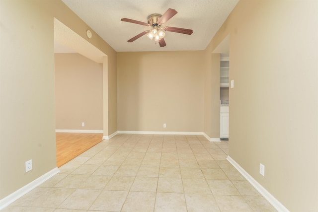 unfurnished room featuring light tile patterned floors, ceiling fan, and baseboards