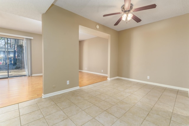 unfurnished room featuring light tile patterned floors, ceiling fan, a textured ceiling, and baseboards