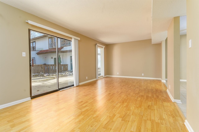 empty room with a textured ceiling, baseboards, and wood finished floors