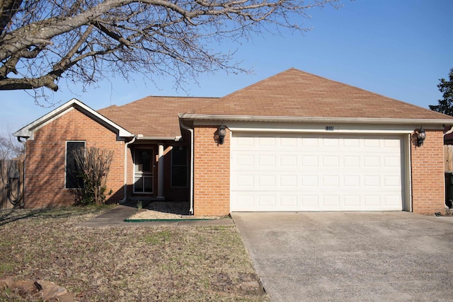 ranch-style home featuring driveway, brick siding, an attached garage, and a shingled roof