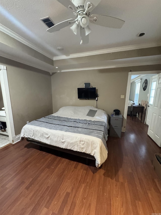 bedroom featuring a ceiling fan, visible vents, crown molding, and wood finished floors