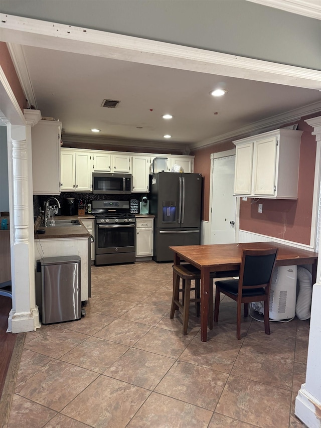 kitchen with stainless steel appliances, a sink, visible vents, ornamental molding, and backsplash