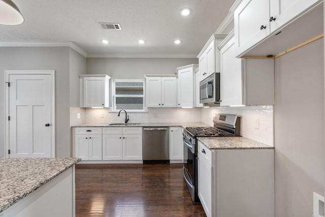 kitchen featuring appliances with stainless steel finishes, white cabinets, visible vents, and a sink