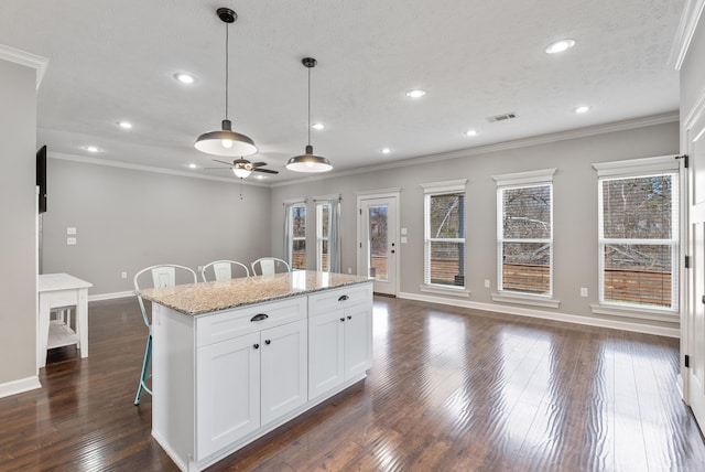 kitchen featuring dark wood-style floors, crown molding, and a kitchen breakfast bar