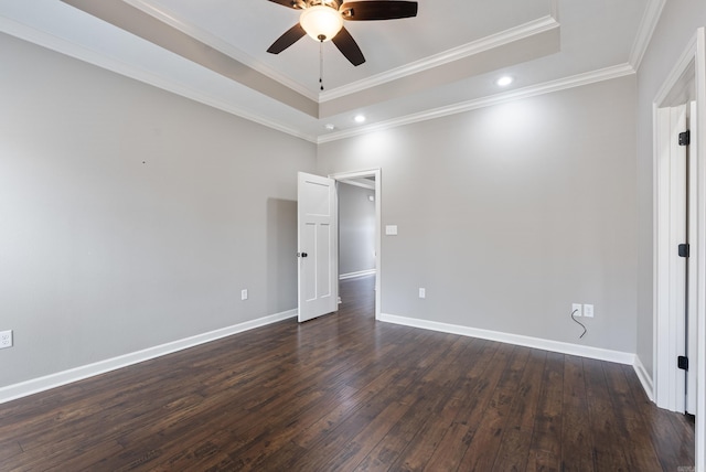 unfurnished room with baseboards, a raised ceiling, ceiling fan, ornamental molding, and dark wood-type flooring