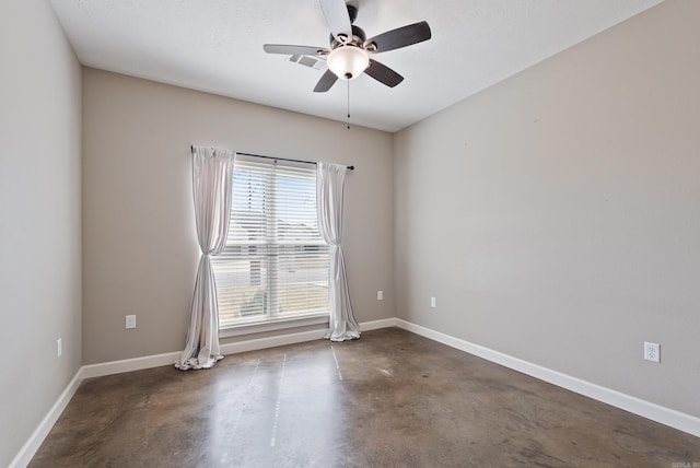 spare room with a ceiling fan, finished concrete flooring, and baseboards