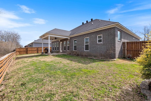 back of house featuring a yard, brick siding, a fenced backyard, and a ceiling fan