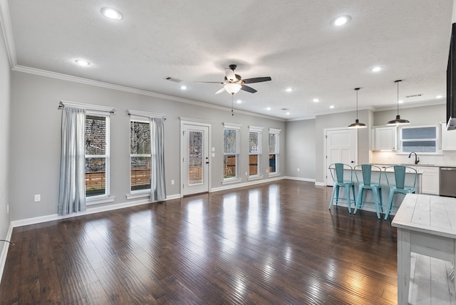 unfurnished living room featuring dark wood finished floors, a ceiling fan, crown molding, a textured ceiling, and a sink