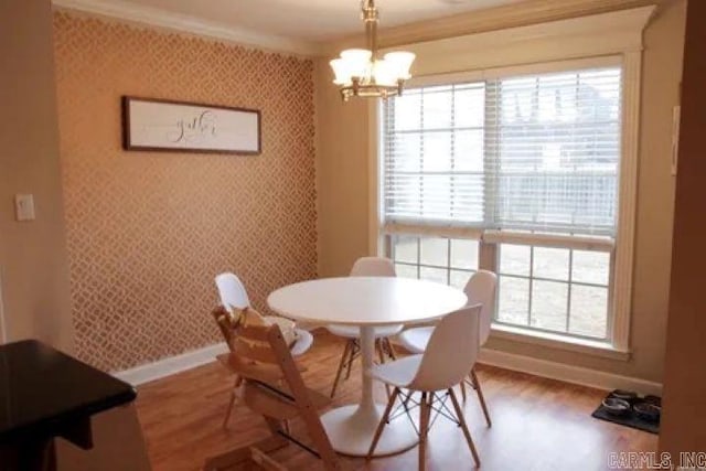 dining room featuring wallpapered walls, crown molding, baseboards, a chandelier, and wood finished floors