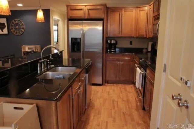 kitchen with light wood-type flooring, brown cabinets, a sink, dark countertops, and stainless steel appliances