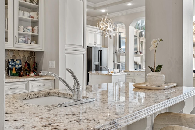 kitchen with high quality fridge, light stone counters, white cabinets, and a sink