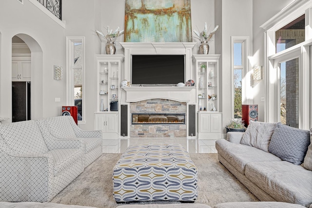 living area with arched walkways, a fireplace, a towering ceiling, and tile patterned floors