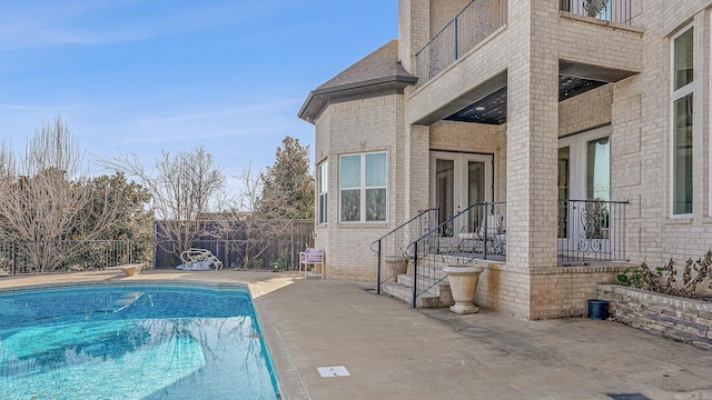 view of pool featuring a fenced in pool, french doors, a patio, fence, and a diving board