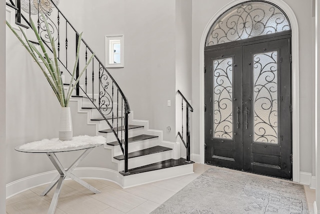 entrance foyer with baseboards, stairway, and french doors