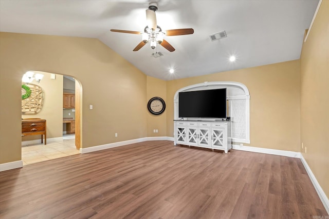 unfurnished living room featuring arched walkways, visible vents, lofted ceiling, and light wood finished floors