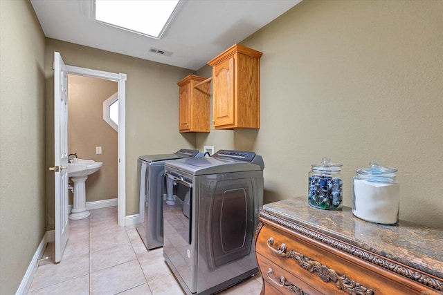 clothes washing area with cabinet space, baseboards, visible vents, washer and dryer, and light tile patterned flooring