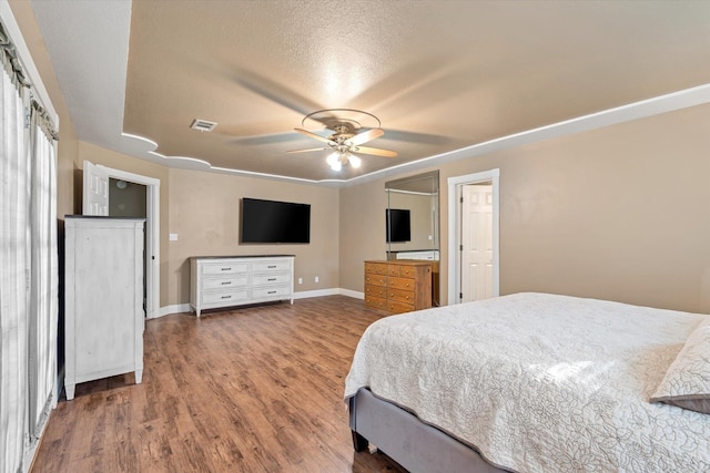 bedroom featuring visible vents, ceiling fan, a textured ceiling, wood finished floors, and baseboards