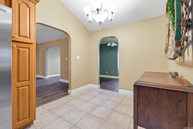 interior space with arched walkways, light tile patterned floors, baseboards, and an inviting chandelier