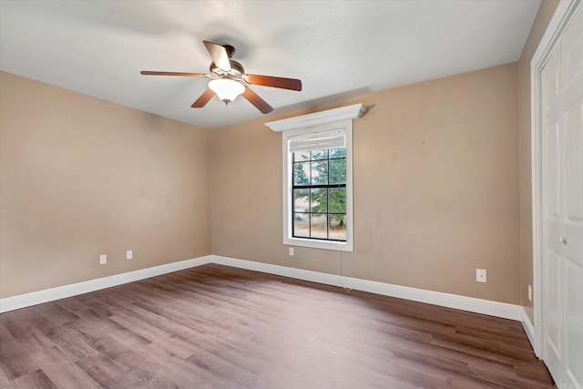 empty room with a ceiling fan, baseboards, and wood finished floors