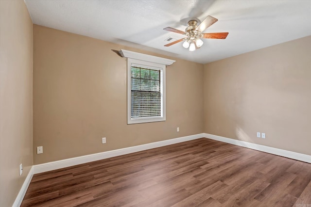 spare room with visible vents, wood finished floors, a ceiling fan, and baseboards