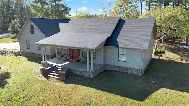 view of front of house featuring stone siding, a shingled roof, a porch, and a front yard