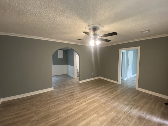 spare room featuring arched walkways, ornamental molding, a ceiling fan, a textured ceiling, and wood finished floors