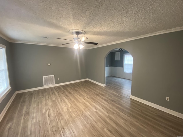 unfurnished room with arched walkways, dark wood-type flooring, visible vents, and crown molding