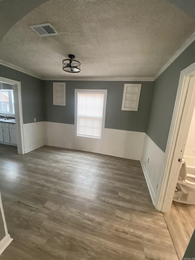 unfurnished dining area with ornamental molding, a wainscoted wall, visible vents, and plenty of natural light