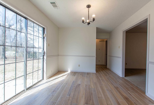 empty room featuring a healthy amount of sunlight, visible vents, and light wood finished floors