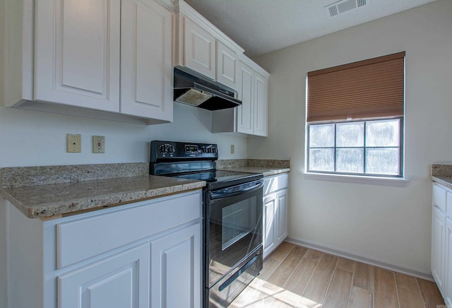 kitchen featuring light wood finished floors, visible vents, white cabinets, under cabinet range hood, and black / electric stove