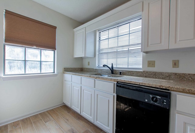 kitchen with light wood-style flooring, a sink, white cabinetry, black dishwasher, and light countertops