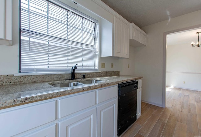 kitchen with light wood finished floors, black dishwasher, white cabinets, a chandelier, and a sink