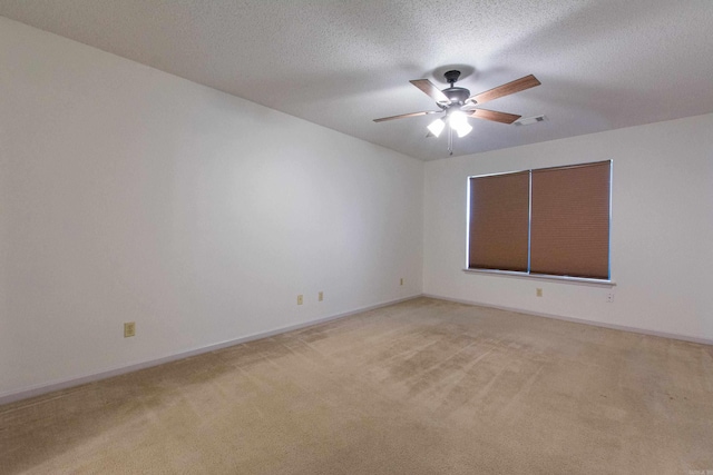 empty room with baseboards, visible vents, light colored carpet, ceiling fan, and a textured ceiling