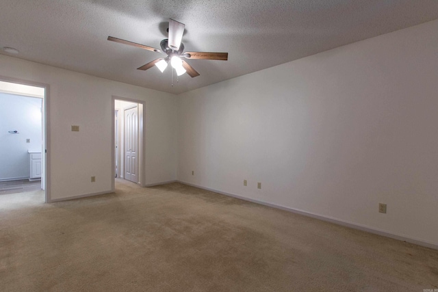 unfurnished room with a ceiling fan, light carpet, a textured ceiling, and baseboards