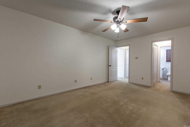 unfurnished bedroom with a textured ceiling, connected bathroom, light carpet, a ceiling fan, and baseboards