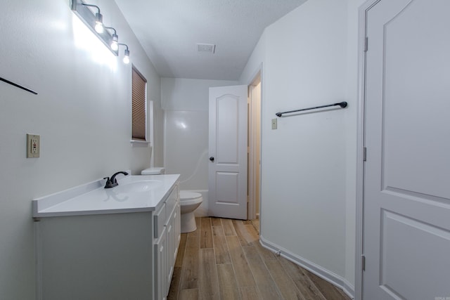 bathroom featuring visible vents, toilet, a textured ceiling, vanity, and wood finished floors