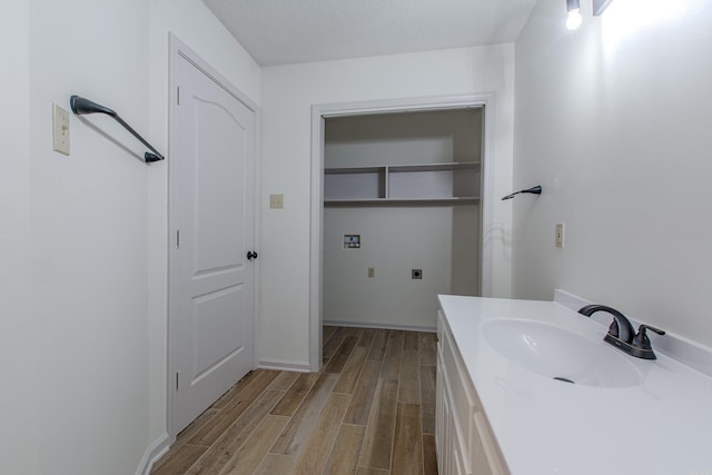 bathroom with a textured ceiling, baseboards, wood finished floors, and vanity