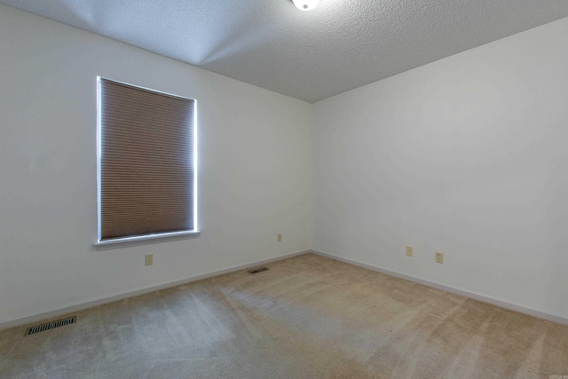 spare room with baseboards, a textured ceiling, visible vents, and carpet flooring