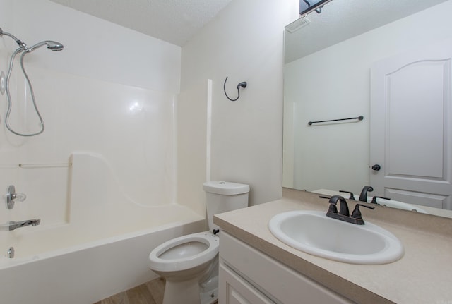 full bathroom with toilet, wood finished floors, a textured ceiling, vanity, and washtub / shower combination