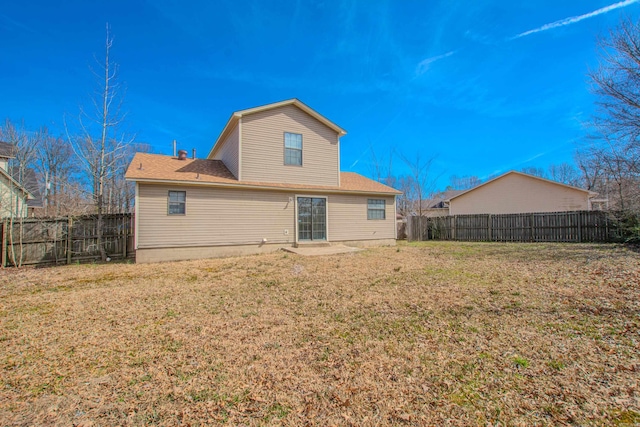 rear view of house featuring a fenced backyard and a lawn