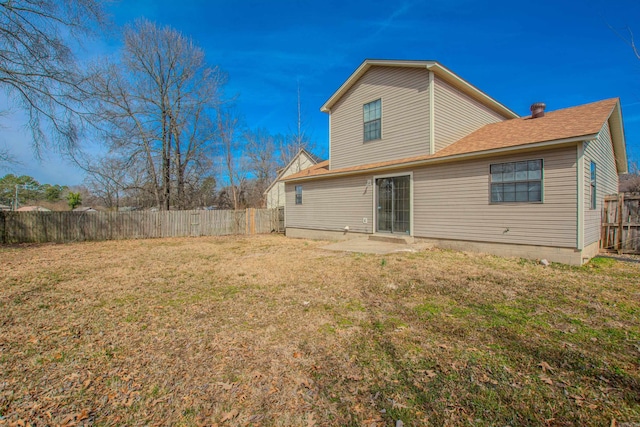 back of house with a yard and a fenced backyard