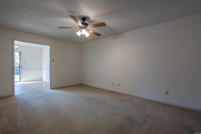 unfurnished room featuring baseboards, a ceiling fan, a textured ceiling, and light colored carpet