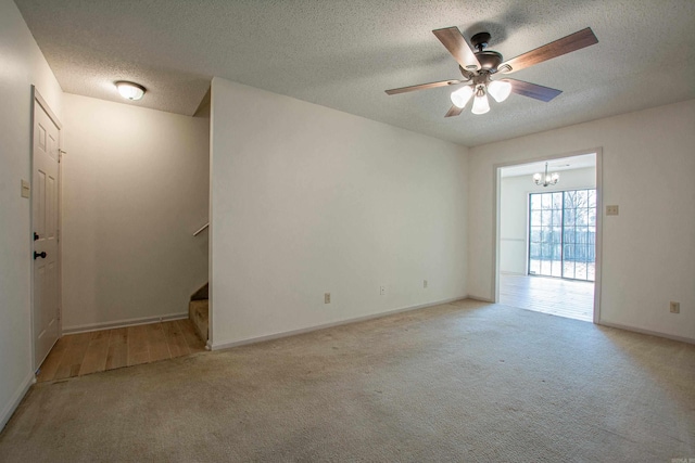 unfurnished room with stairs, a textured ceiling, ceiling fan with notable chandelier, and light colored carpet