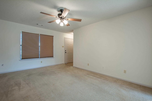 unfurnished room with visible vents, light carpet, a textured ceiling, and baseboards