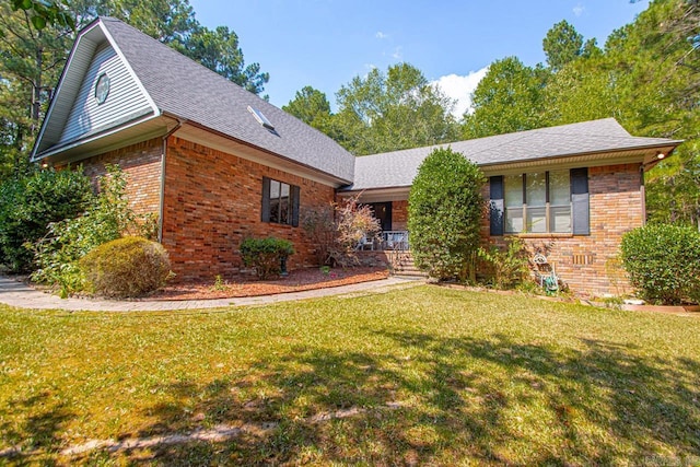 view of front of home with covered porch, roof with shingles, brick siding, and a front lawn