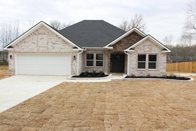 view of front of house with concrete driveway, roof with shingles, an attached garage, fence, and a front yard