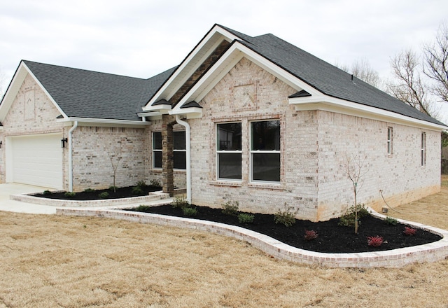 view of front of property with a garage, brick siding, driveway, and roof with shingles