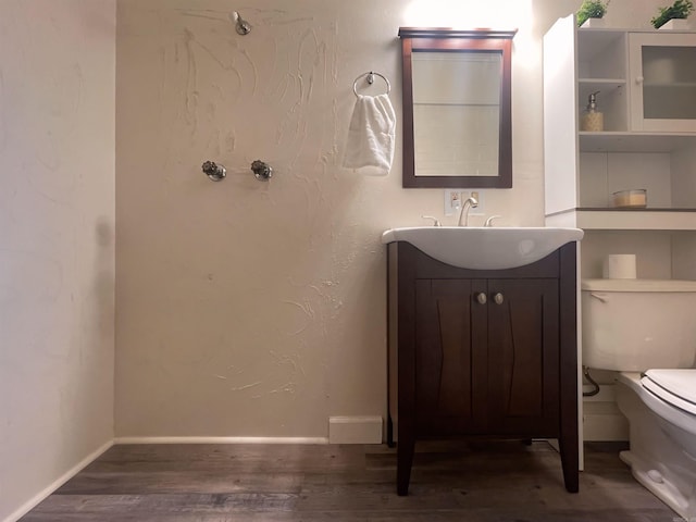 bathroom featuring vanity, wood finished floors, toilet, and baseboards