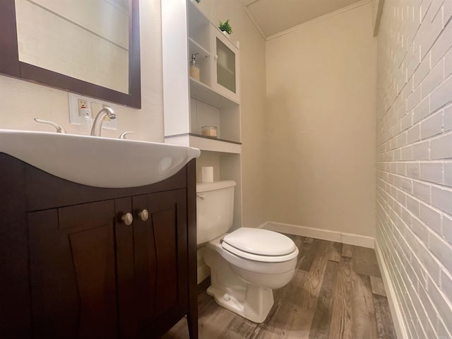 half bathroom with vanity, wood finished floors, toilet, and baseboards